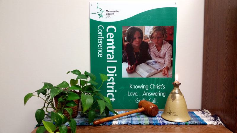 A Central District Conference sign, a gavel, and an oil lamp on a table